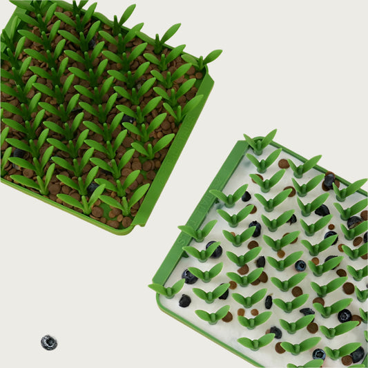 Image of two of the Grass style Foraging Mats, side by side. One has kibbles in the bottom and the other has a mix of kibbles, blueberries and goat milk.
