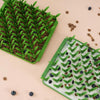 Image of two of the Grass style Foraging Mats, side by side. One has kibbles in the bottom and the other has a mix of kibbles, blueberries and goat milk.