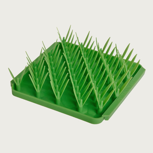 Photo of the Tall Tails Foraging Mat in Grass design. It is a bright green square with diagonal rows of dual-bladed silicone "grass".
