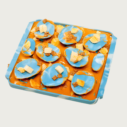 Image of the Rock style Foraging Mat with a mix of peanut butter, cut banana, and kibbles spread in it.