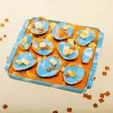 Image of the Rock style Foraging Mat with a mix of peanut butter, cut banana, and kibbles spread in it.
