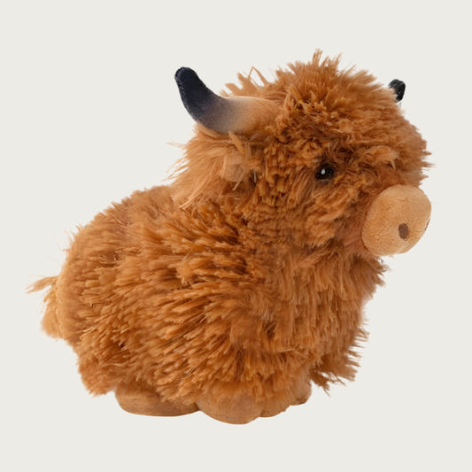 Side view of the shaggy highland cow dog toy, which shows its short and compact body.