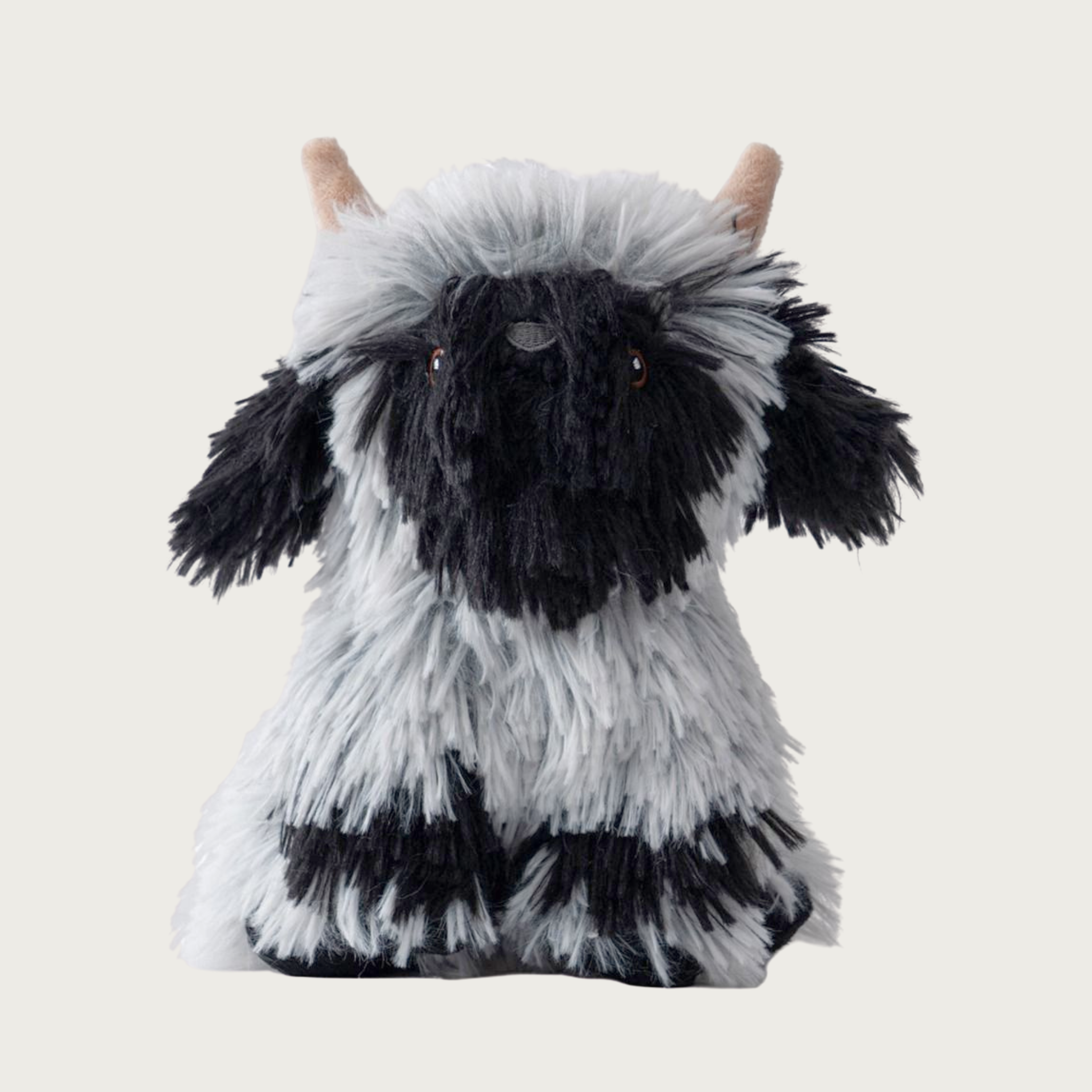 Shaggy, faux fur covered plush dog toy shaped like a Highland Sheep. It's body is a heathered grayish-white, with black accents on its feet, ears, and snout. Embroidered eyes and nose details.