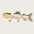 Load image into Gallery viewer, Side, lengthwise view of a plush trout dog toy made of 3 segments attached by a beige rope. The body segments are multicolored with stripes of olive green, pale pink, beige, and white. The fish has an open mouth, and embroidered lifelike facial details.
