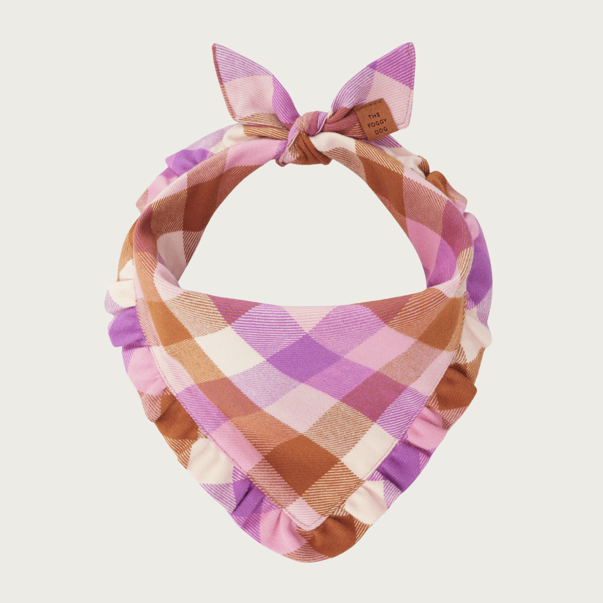 A flannel dog bandana with a plaid pattern in shades of purple, brown and cream, with ruffled edges and tied at the top.