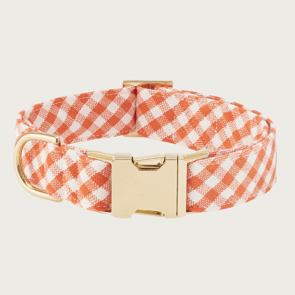 A dog collar with a white and orange gingham pattern and polished gold-tone buckle & hardware.