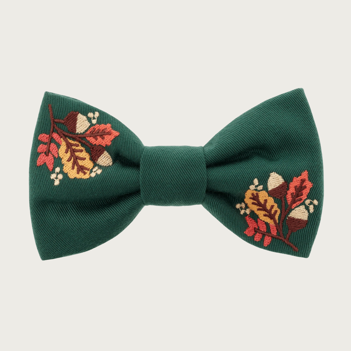 Forest green bow tie for dogs, with two embroidered sections featuring autumn leaves & acorns, in the top left and bottom right of the bow. 