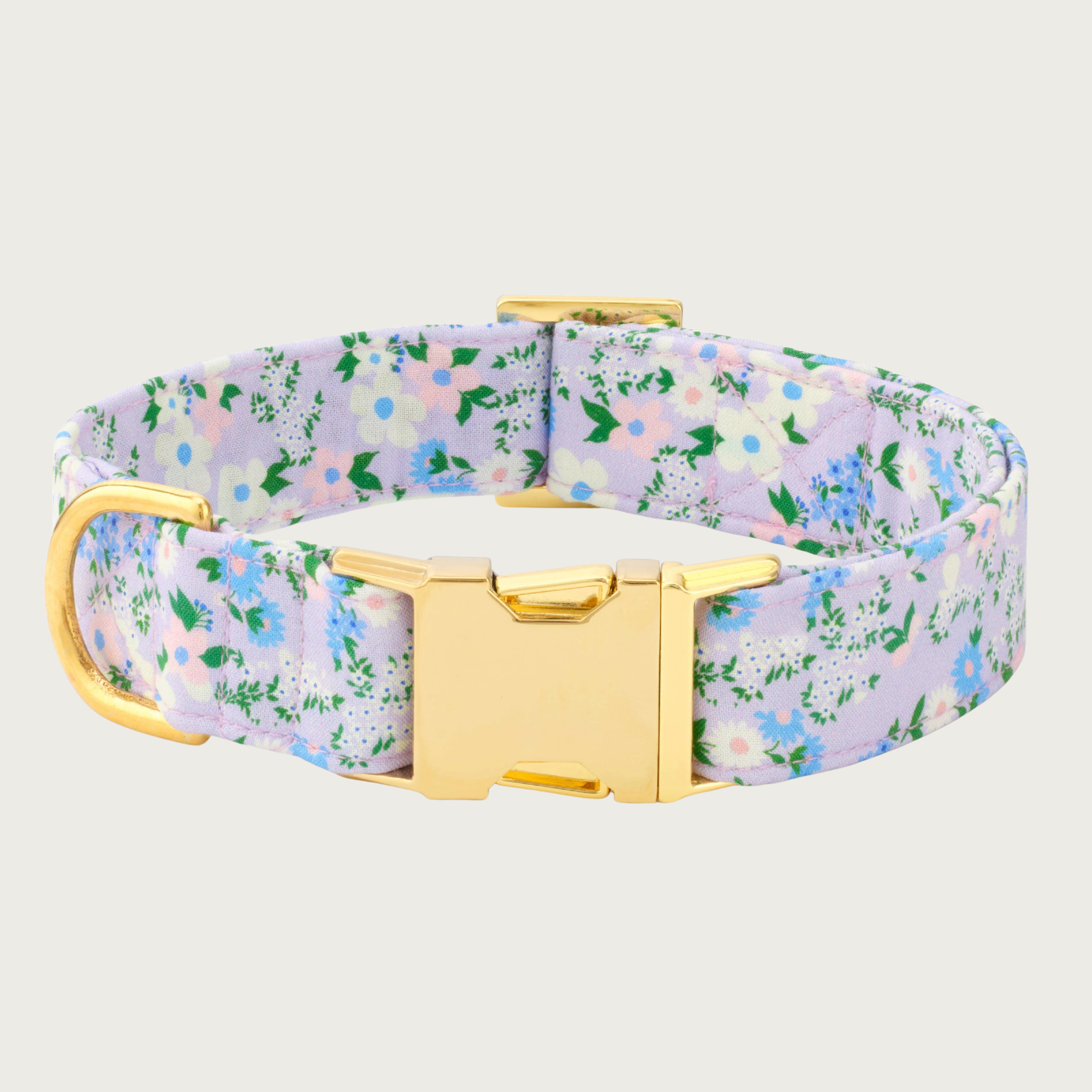 Delicate floral dog collar with a pale lilac background color, and with a print of different types of wildflowers in shades of blue, white, and pink. Gold-toned hardware.