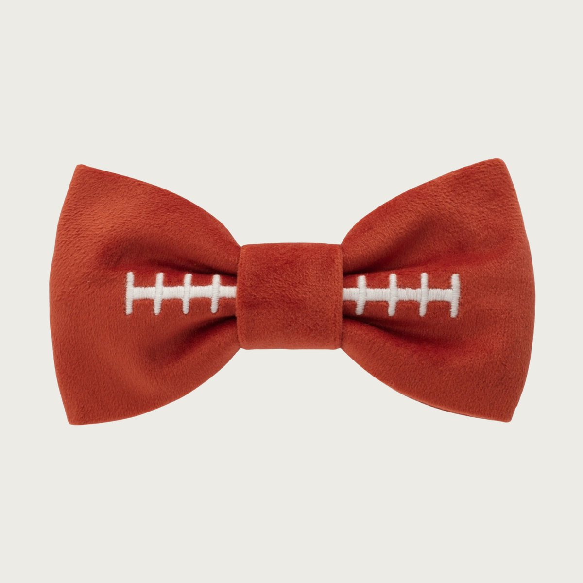 Rust brown, faux suede looking bow tie for dogs, with white embroidery in the center to look like a football's laces.
