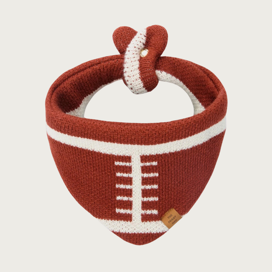 Thick, sweater knit dog bandana designed to look like a football. Its base color is rust brown, and features white stitching to look like the white laces & stitching on a football. Closes at the neck with a small snap.