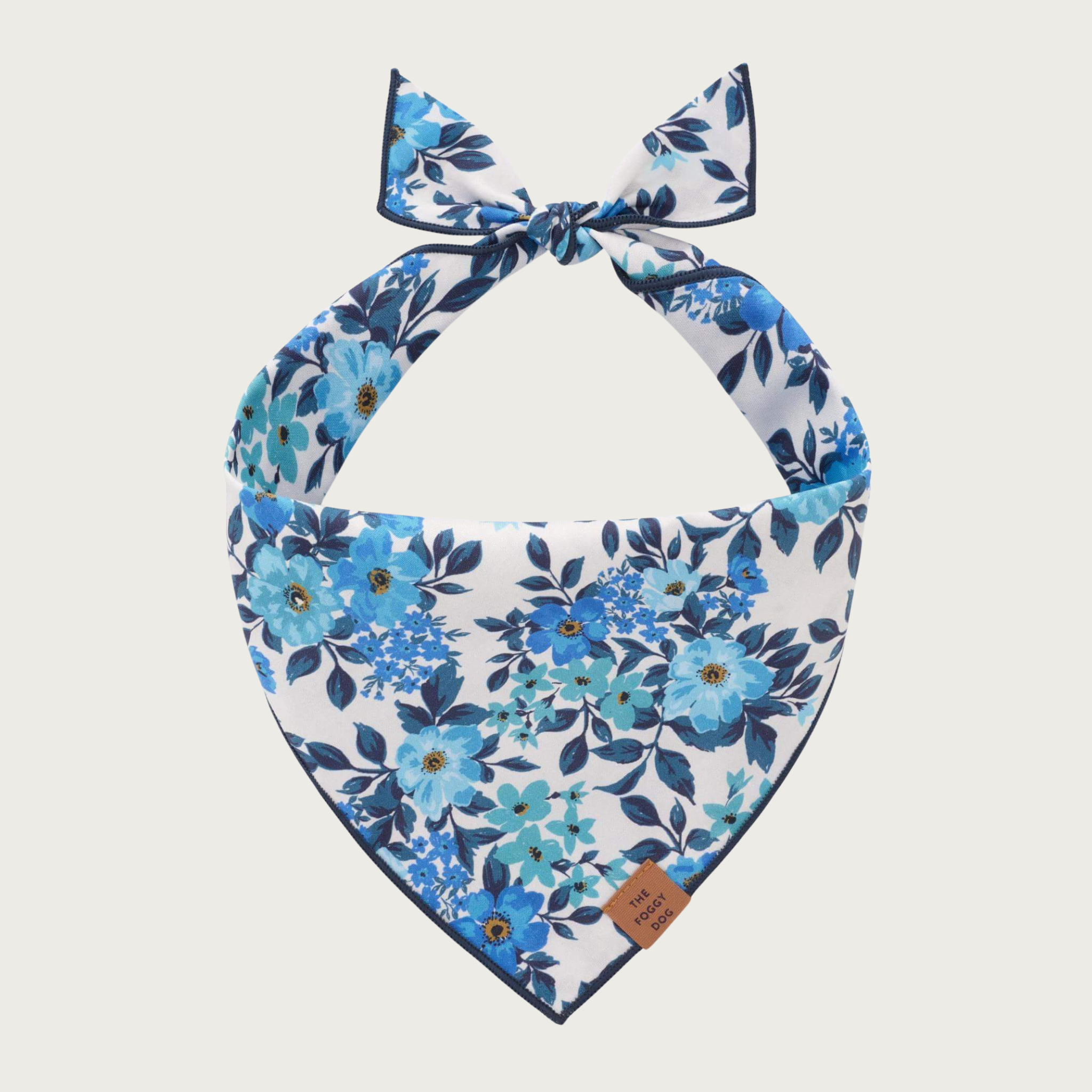 Blue floral dog bandana on a white background. Various types of realistic -looking flowers are featured, in a range of blue tones.