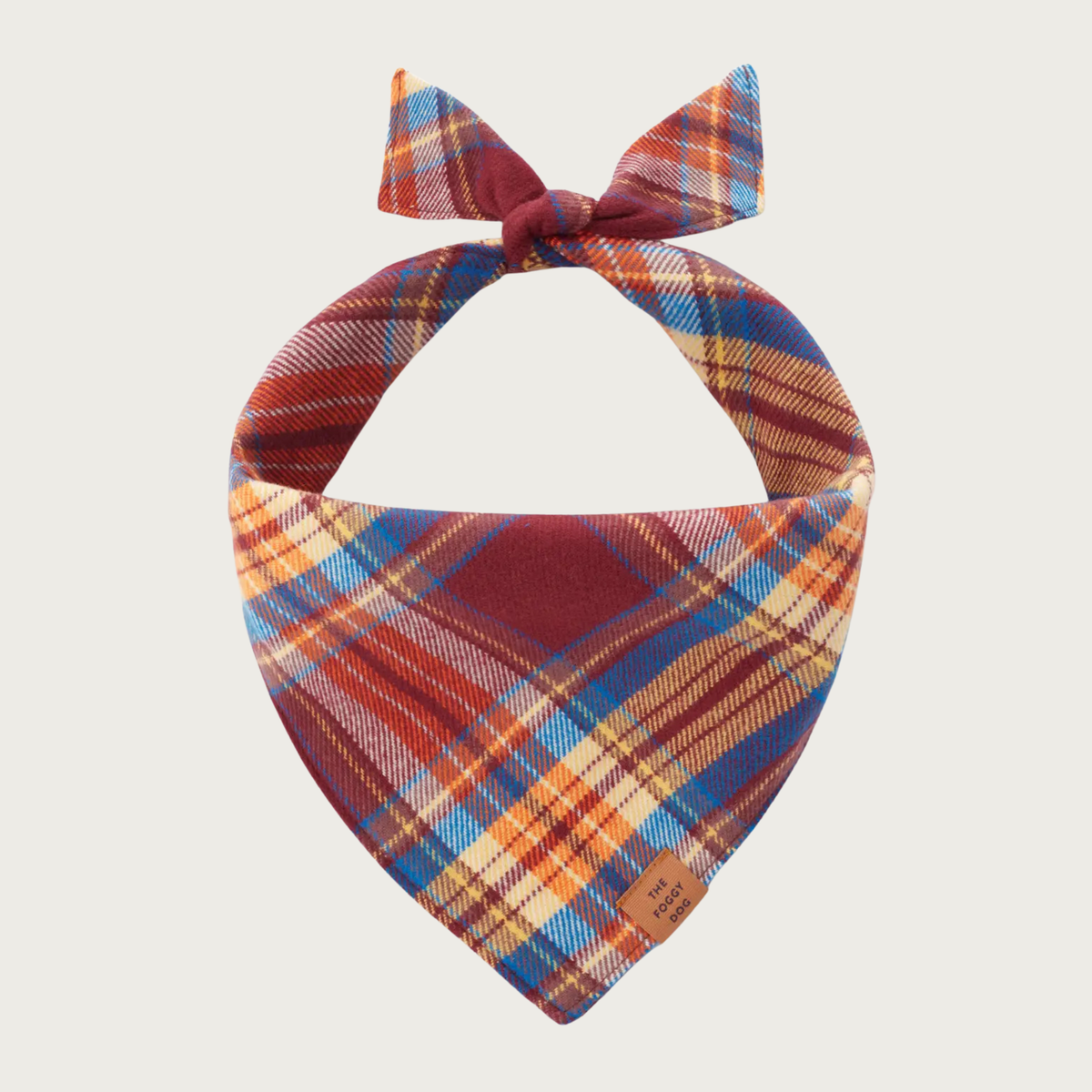 A flannel dog bandana tied at the top, featuring a plaid pattern of rust, gold, and medium blue.
