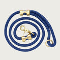 Load image into Gallery viewer, Coiled, navy blue rope dog leash with brass hardware. Fastened on both ends with brass clamps, instead of stitching. O-ring is in the handle part of the leash, with lobster claw style of clasp to connect to collar or harness.
