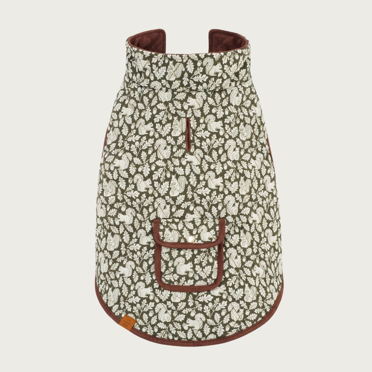 Olive Dog Jacket reversed to show the printed side, which is a dark olive green background with ivory squirrels, acorns, and leaves print. Small pocket and leash opening are visible, and trimmed in brown.
