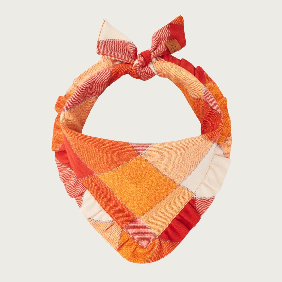 A flannel dog bandana with a ruffled edge, featuring a warm-toned plaid pattern in shades of orange, rust, and cream, tied in a bow at the top.
