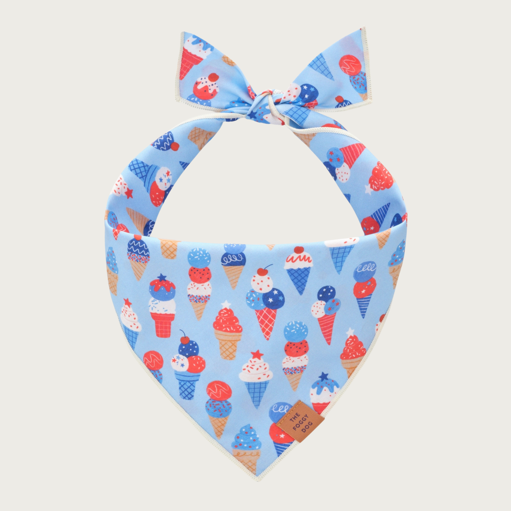 Light blue dog bandana with red, white & blue ice cream cone pattern. Pattern has ice cream cones of different shapes & sizes, and with different toppings.