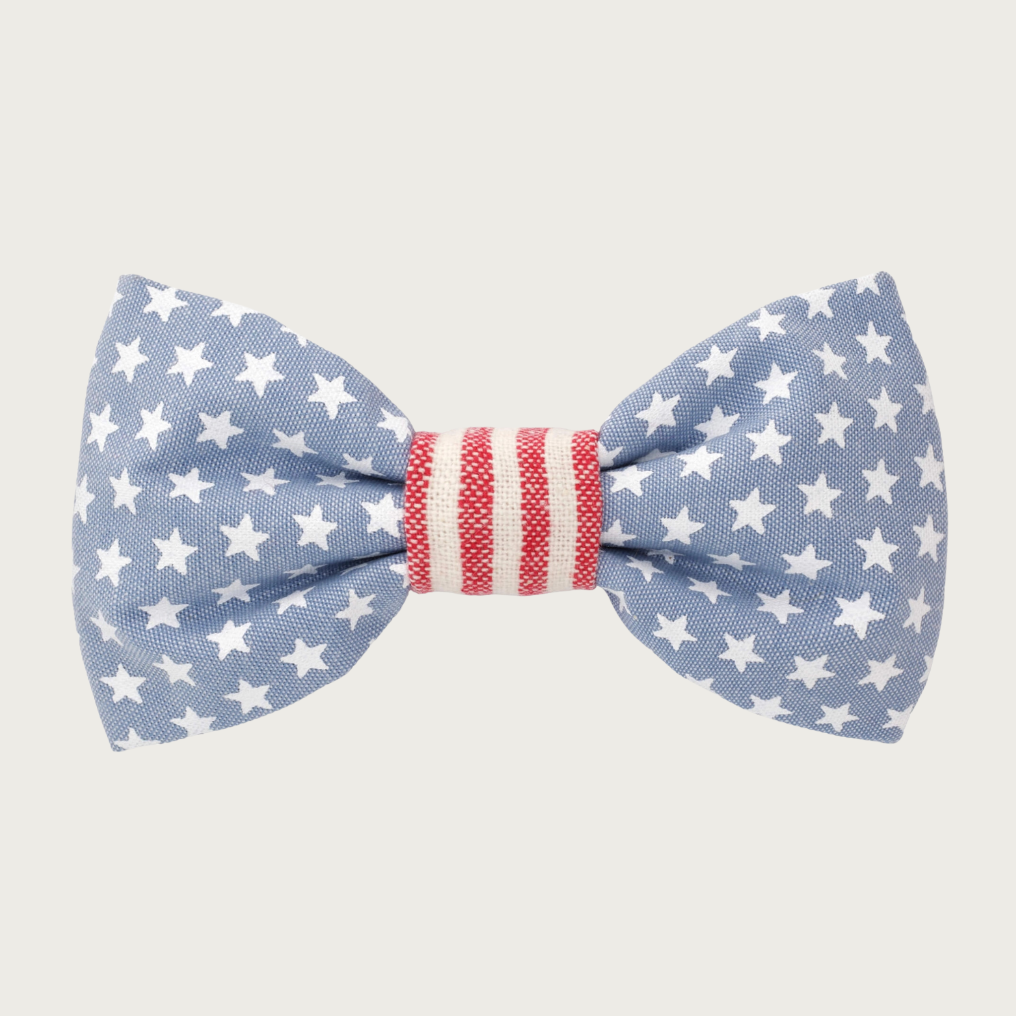 Oxford cloth dog bow tie with stars & stripes motif. Bow is light chambray blue with white stars. Center has white and pale red vertical stripes.