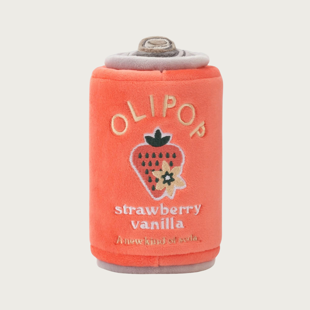 A plush soda can-shaped dog toy in deep peach color, featuring embroidered text that reads 'OLIPOP strawberry vanilla' and an embroidered strawberry with vanilla blossom graphic.