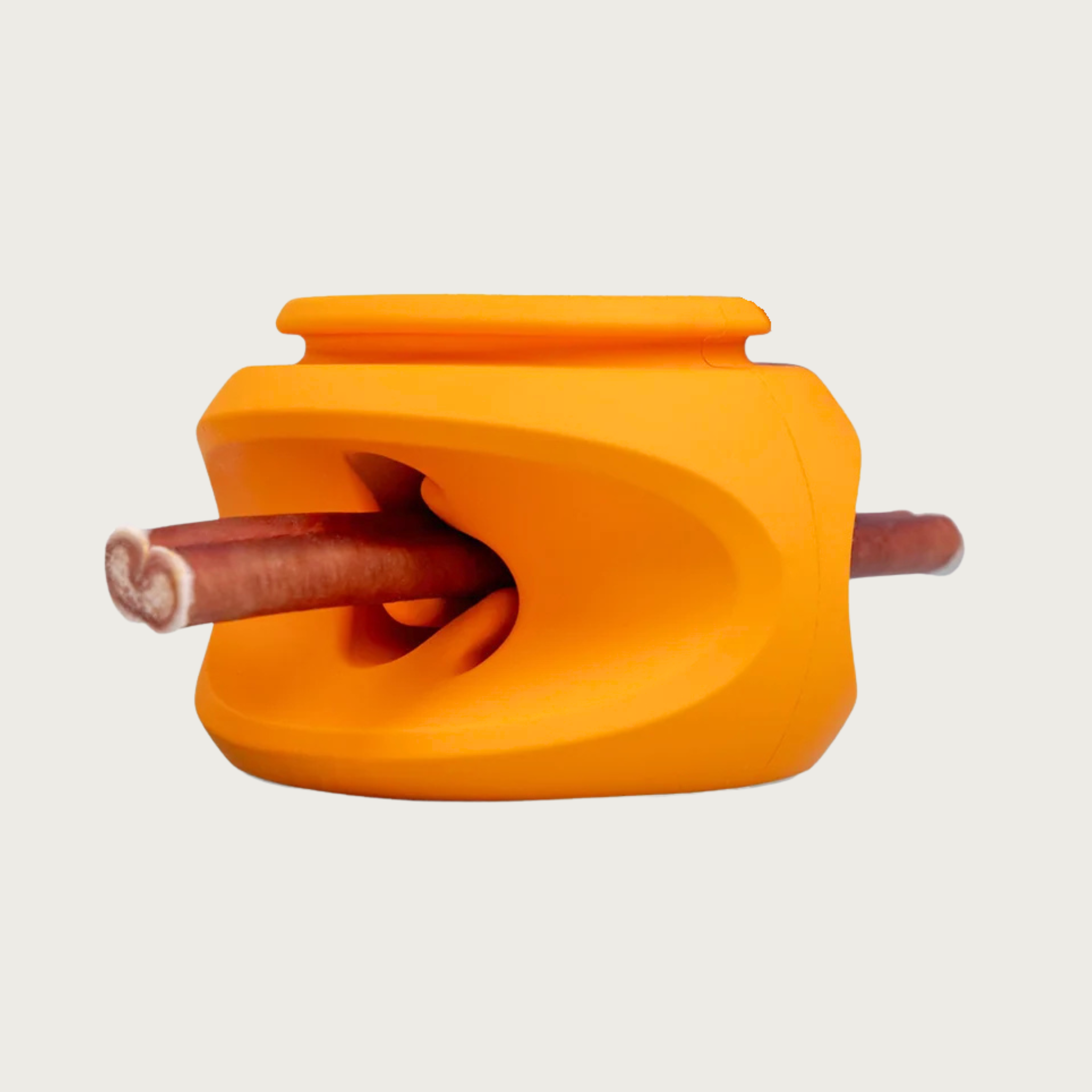 An orange rubber dog toy shown with a bully chew stick inserted horizontally through its indented center.