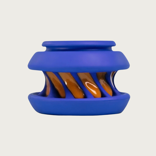A blue rubber dog toy with an indented, twisted center with ridges, that is smeared with peanut butter.