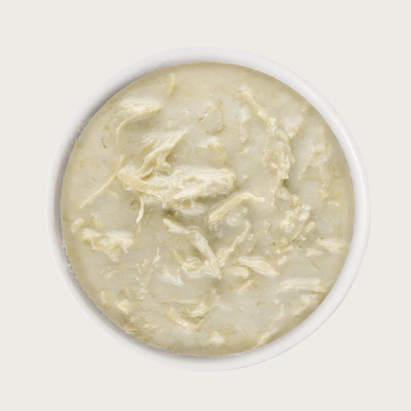 A close-up image of a dish of Weruva Wx Phos Focused Chicken Formula in Gravy. It is beige in color, and shows shreds of chicken in a creamy looking gravy.