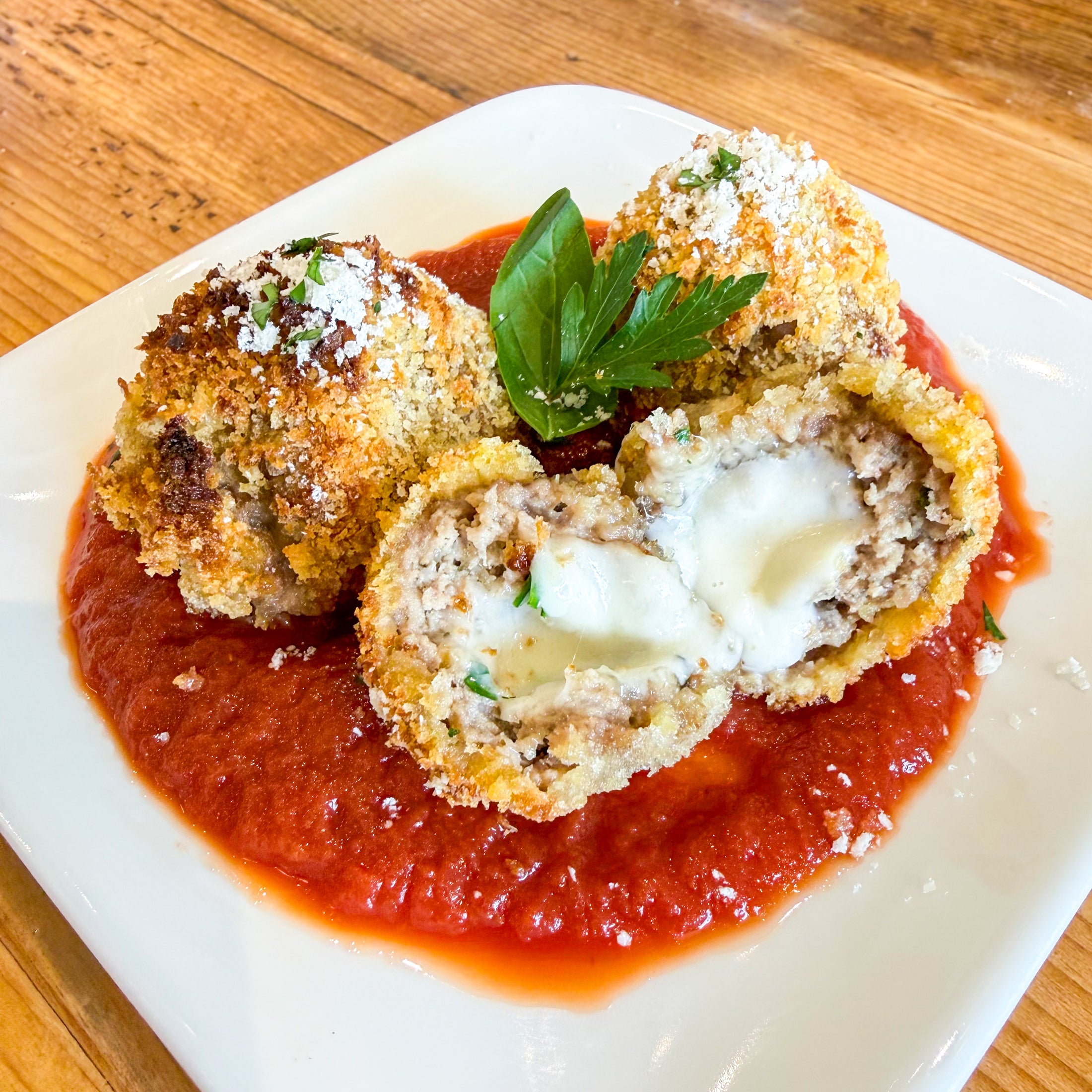 Alternate view of the arancini dog treats, showing one cut open to expose the melted mozzarella cheese center.