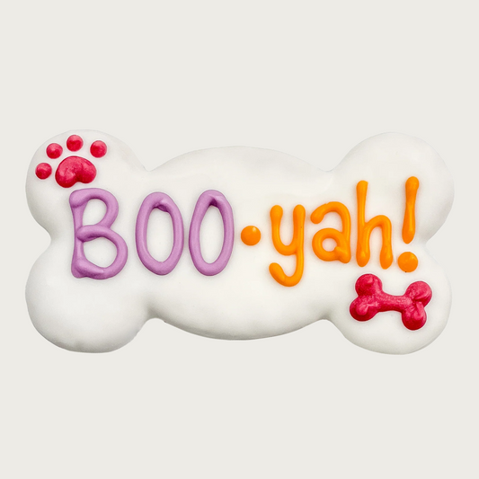 White dog bone-shaped dog cookie with 'BOO-yah!' text in lavender and orange, with red paw print and dog bone accents.