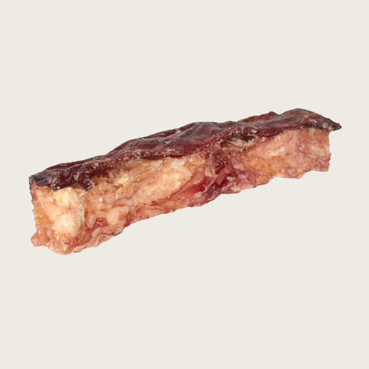 Long, rectangular shaped dog treat that looks like a thick slice of meat topped with a thin, darker layer of flattened jerky.