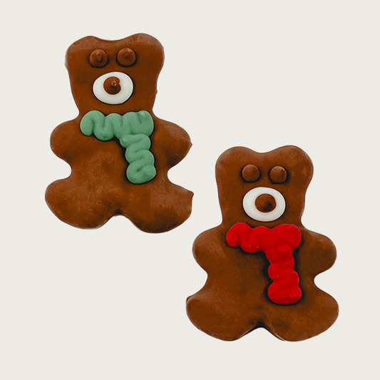 Two decorated dog cookies, shaped like brown bears. One is wearing a green scarf, the other is wearing a red scarf. Both have eyes & snout details.