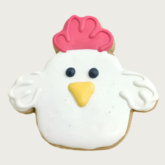 Dog cookie shaped like a white chicken with a red crown, black eyes and yellow beak.