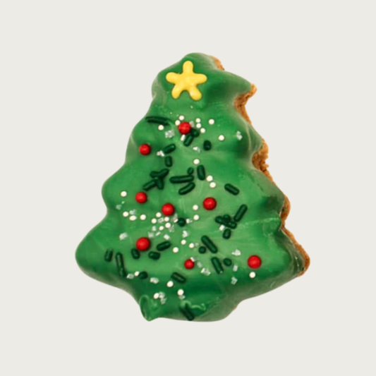 Green Christmas tree-shaped dog cookie with red, green, and white sprinkles and a frosting gold star.