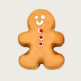 Load image into Gallery viewer, Tan, gingerbread man shaped dog cookie with a simple white smiley face and three red & white buttons down its chest.
