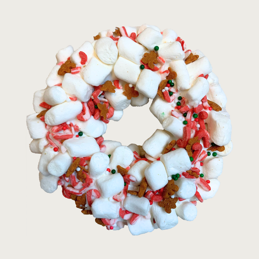 Christmas themed, donut shaped dog cookie covered with mini marshmallows, and accented with tiny candy canes, brown gingerbread men and red, white & green nonpareils. 