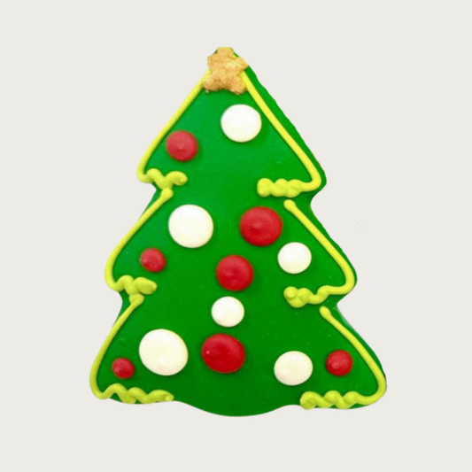 Decorated dog cookie in the shape of a Christmas tree, with a gold sprinkled star on top and red and white dot "ornaments".