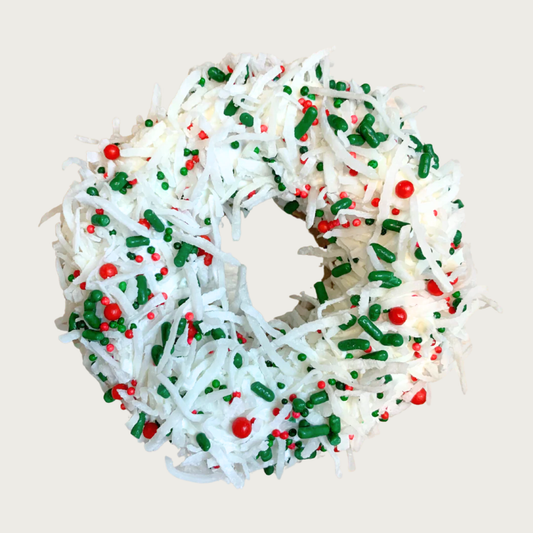 Christmas themed, donut shaped dog cookie covered with shredded coconut, and accented with red, white & green sprinkles and nonpareils. 