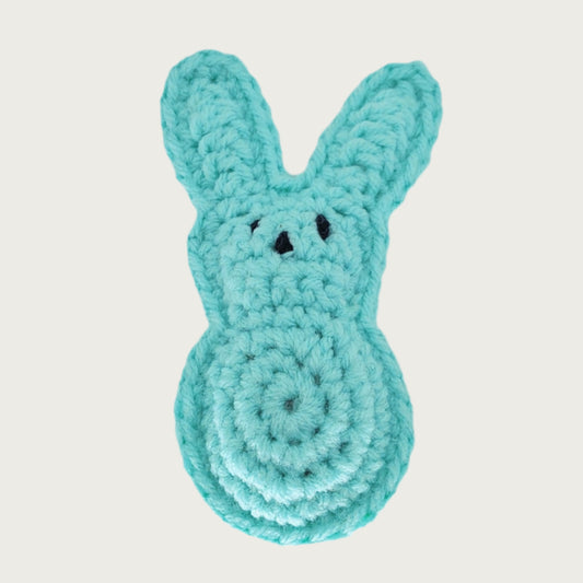 Crocheted bunny cat toy that looks like a marshmallow Peep candy. Simple bunny shape with 2 long ears on a rounded head with round body. Black knit eyes and nose.