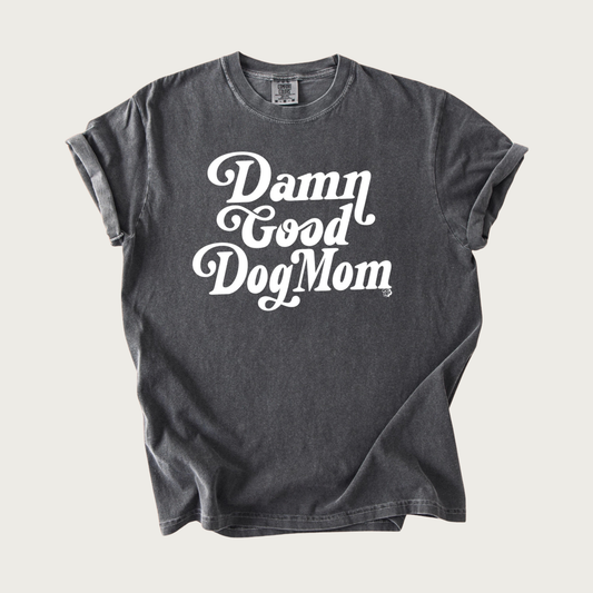 Garment washed, dark gray t-shirt with 'Damn Good Dog Mom' script text in white, in center of shirt.