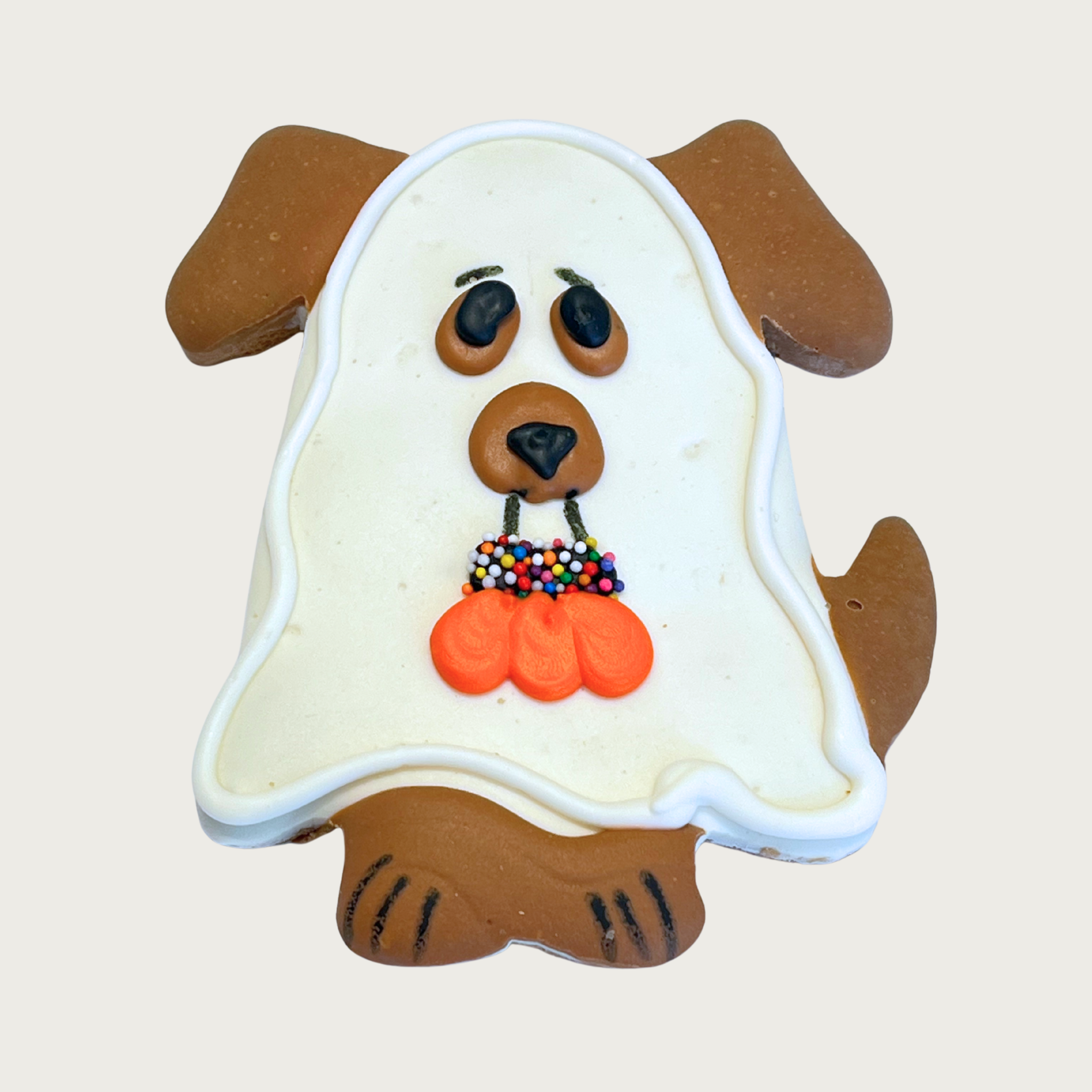 Halloween-themed dog cookie, shaped like a dog wearing a sheet, to look like a ghost. The brown dog's ears, eyes, snout, tail and feet are showing, and it is carrying a pumpkin shaped trick-or-treat bag in its mouth.