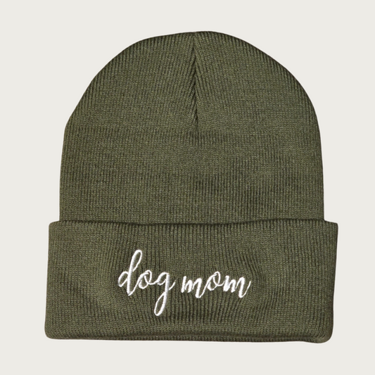 Deep olive green beanie (winter cap) with 'dog mom' in lower case letters white script embroidered on the cuff.