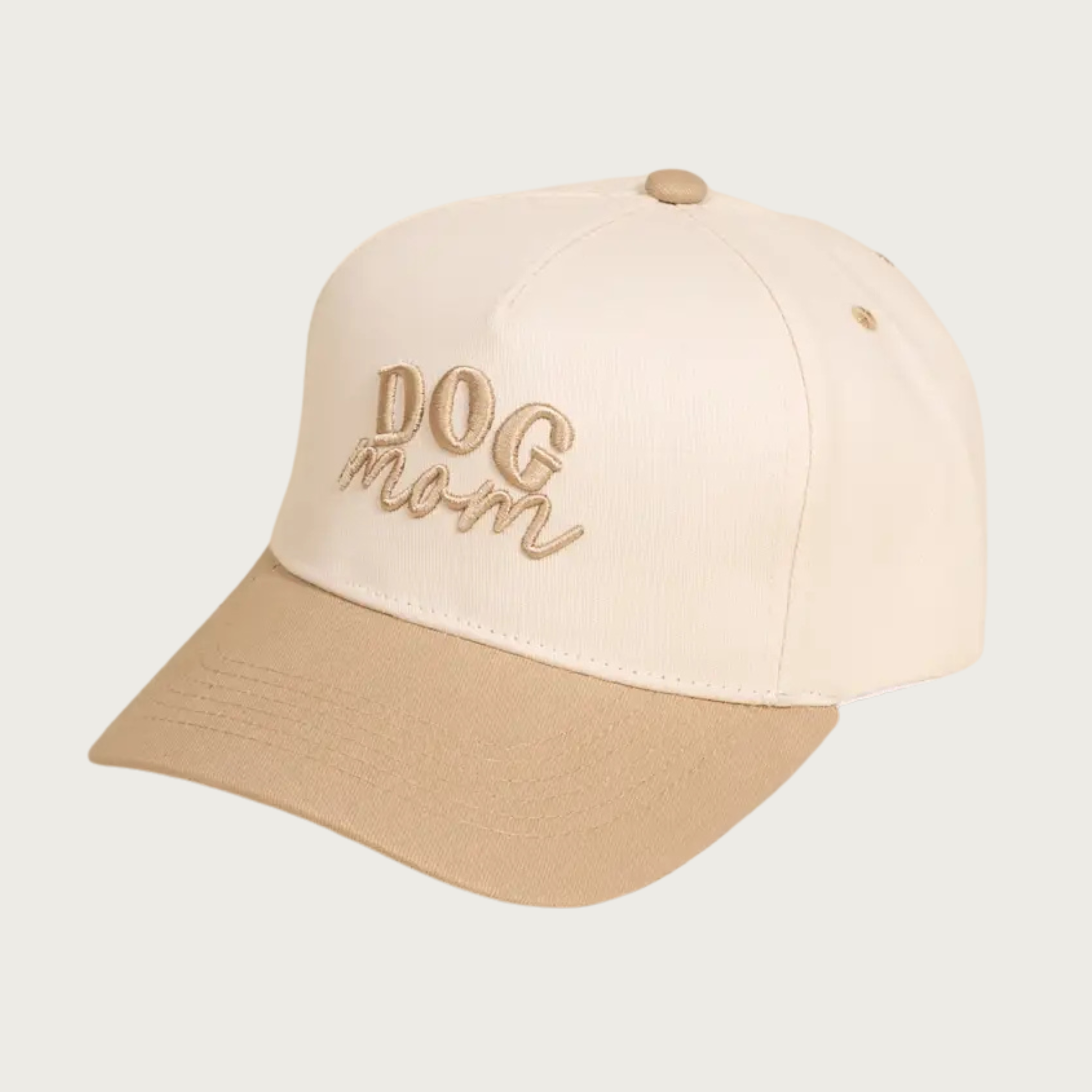 Two-toned baseball cap with ivory body and tan bill & button on top. The cap reads "DOG mom" in embroidered tan text-"DOG" is in all caps, and "mom" is in lower case script text.