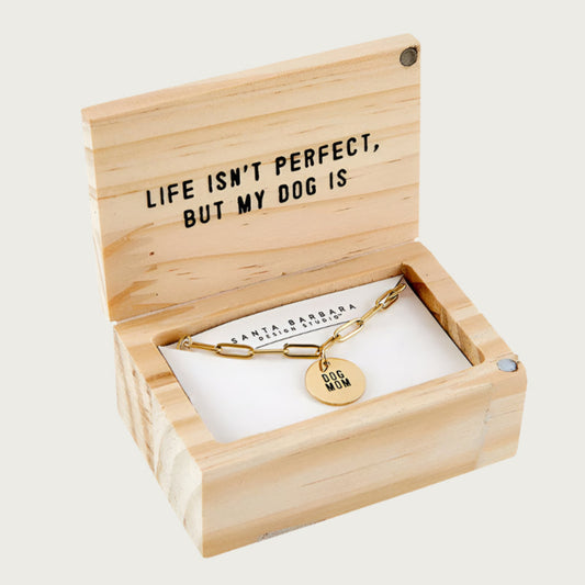 Gold-toned chain link necklace with a small, round gold-toned pendant that reads "Dog Mom", displayed in a wooden gift box. Interior of lid reads 'Life isn't perfect, but my dog is'.