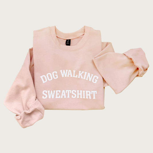 Pale pink crewneck sweatshirt with 'DOG WALKING SWEATSHIRT' in all caps, white text in the center. 