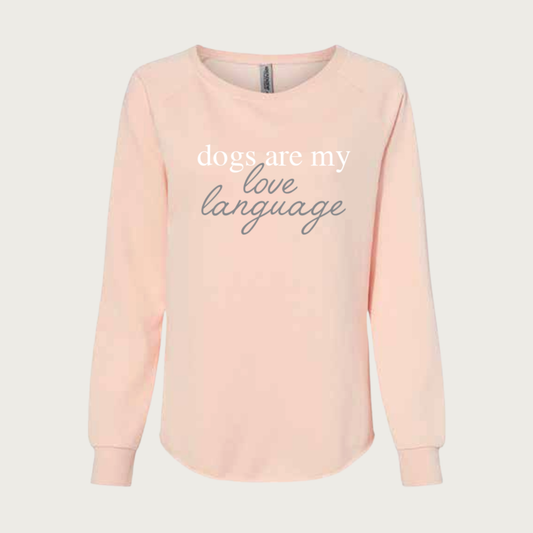 Pale, blush pink crewneck sweatshirt, with text that reads, "dogs are my love language". "Dogs are my" is in white lowercase print, and "love language" is in lowercase gray script.
