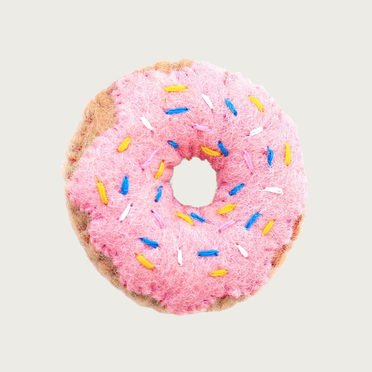 A felted wool donut cat toy with pink frosting and blue, yellow & white sprinkles.