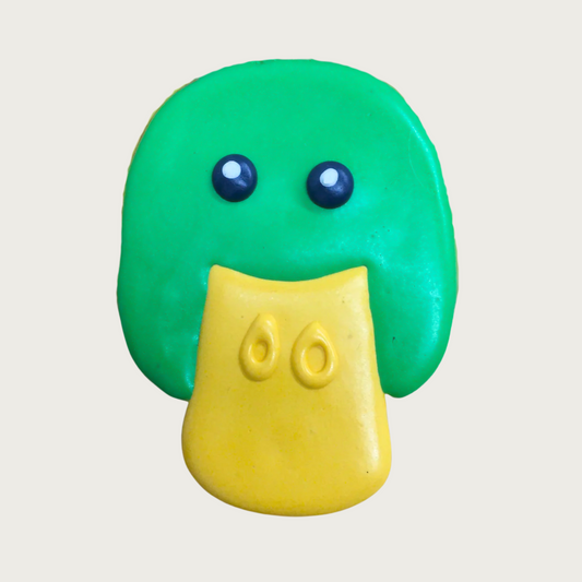 Dog cookie shaped like a mallard duck face, with green head, yellow bill and black eyes.