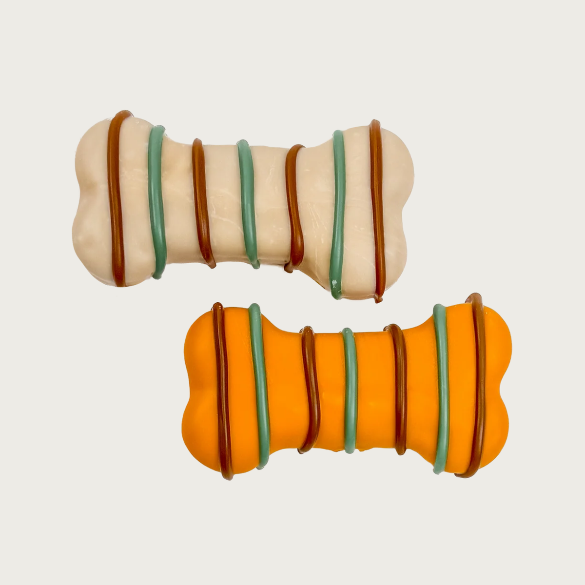 Two dog-bone shaped, decorated dog cookies, offset and displayed side by side. The top cookie is a cream color with deep teal and brown thin stripes, and the bottom cookie is orange with the same decoration.