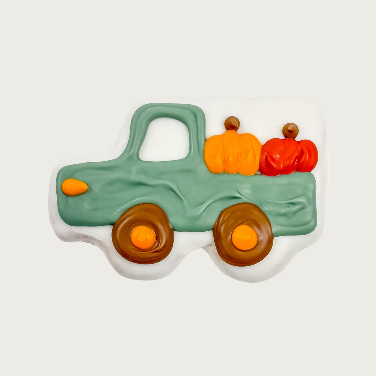 A decorated dog cookie shaped like a dusty green antique pickup truck carrying orange and red pumpkins.