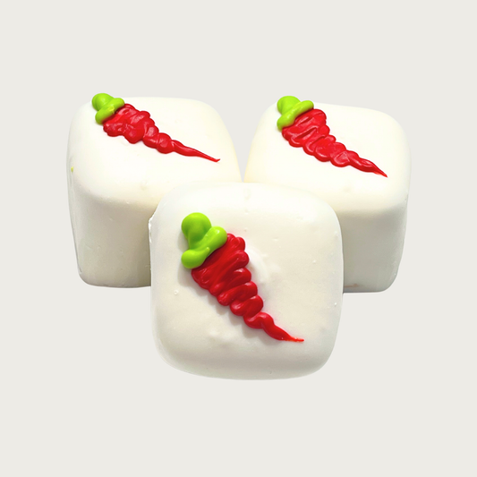 Three square Bon Bon dog treats. They are iced white, and each has a single, iced red chili pepper with green top in the center.