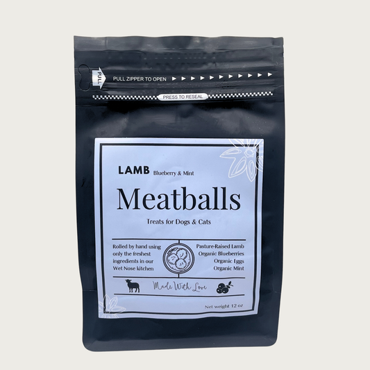 A 12oz black resealable stand-up pouch of Lamb Meatballs dog and cat treats, featuring a pale blue front label with product details and illustrations. Made with Love in the Wet Nose kitchen.