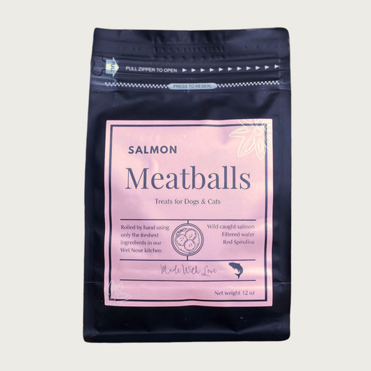 A 12 oz black bag of Salmon Meatballs treats for dogs and cats. Made with Love in the Wet Nose Kitchen. Features wild caught salmon, filtered water, and red spirulina.